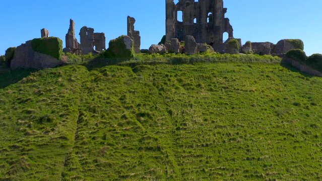 Drone view over the Corfe Castle surrounded by green vegetation in England