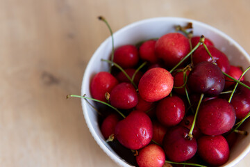 sweet cherry in a white plate on a wooden table close-up	
