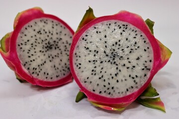 Closeup of a fresh dragonfruit cut in half on a white surface