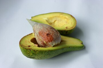 Ripe avocado split into two halves on a white background