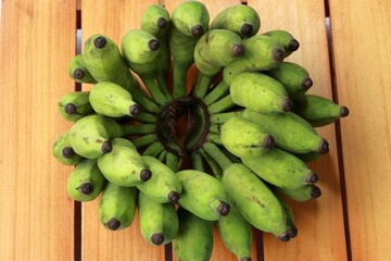 Collection of green, unripe bananas lying side-by-side on a rustic wooden table