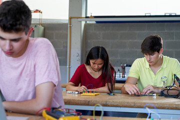 Front view of students concentrated working on their technology class learning to build electronic...