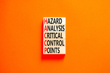 HACCP symbol. Concept words HACCP hazard analysis critical control point on wooden block. Beautiful orange background. Business HACCP hazard analysis critical control point concept. Copy space.