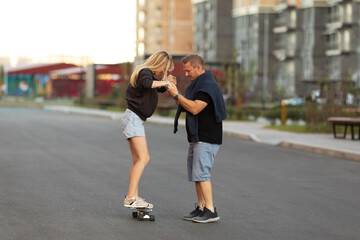 Full length portrait of a happy couple enjoying spending time together skateboarding at sunset.