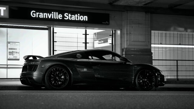 Greyscale of a audi r8 car driving at high speed on the road in the evening