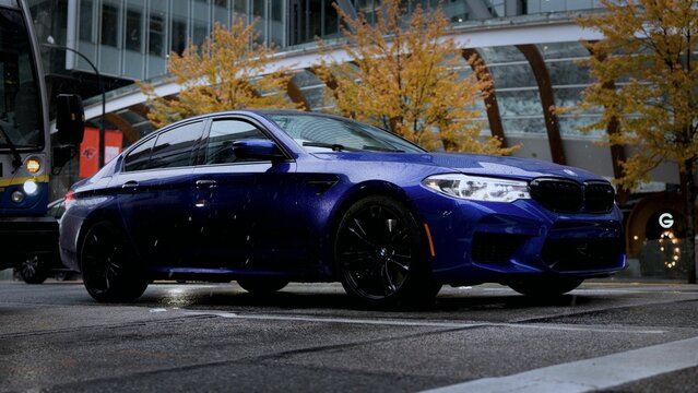 Blue big BMW M5 car driving at high speed on the road in the evening