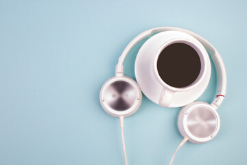 Headphones, mobile phone, idiobook, coffee cup on a blue background. The concept of leisure and learning, hobby. Listen to music, literature. Top view with copy space.