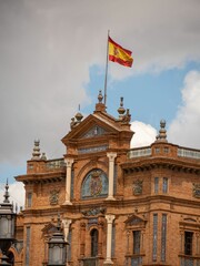 Fototapeta na wymiar Vertical shot of a building with Spanish flag in the central square of Seville, Spain