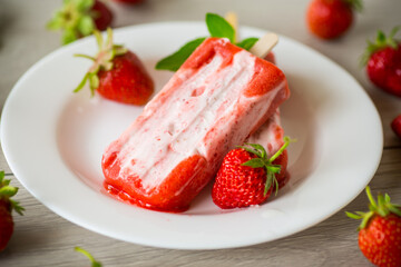 homemade strawberry ice cream on a stick in a plate with strawberries