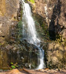 Fototapeta na wymiar Vertical shot of a splashing cascading waterfall in the mountains