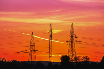 Three metal poles with power lines at sunset, anthropomorphic silhouette, industrial photography,...