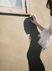 Girl touching her shadow on the wall by side, vertical shot
