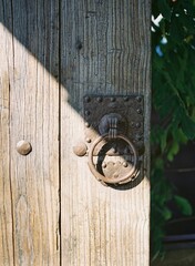 Vertical shot of aweathered sunny wooden door with an old round door handle