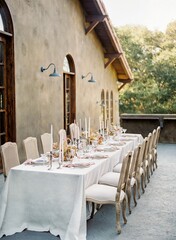 Wedding reception table with white cloth cover by a rural wooden house