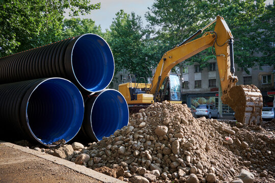 Large plastic corrugated pipes for water supply lie on the street in the city.