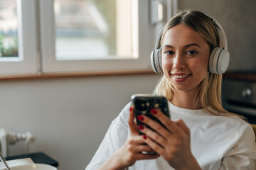 A pretty young Caucasian woman with headphones looking at the camera.