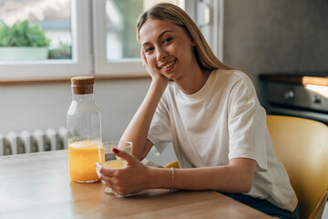 A beautiful woman is enjoying orange juice at home.