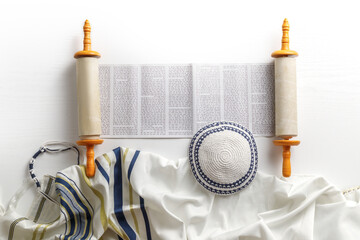 Torah scroll with prayer shawl tallit and kippah on a light background