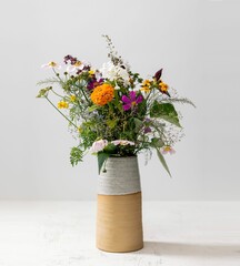 Vertical shot of a bouquet of wild flowers in a vase isolated on a white background