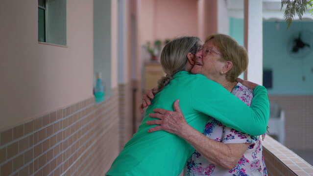 Warm family reunion, adult daughter embracing elderly mother. Generational hug, senior lady being visited by relatives