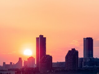 Bright sun setting in orange sky above Jersey City skyline in the USA