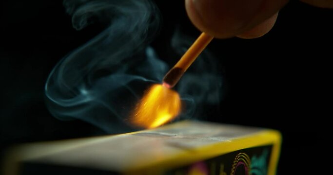 Match ignite, hand and orange flame with smoke and smoking in studio with dark background. Flames, fire and blackout with matchbox and power outage with burning light and glow with risk and sparks