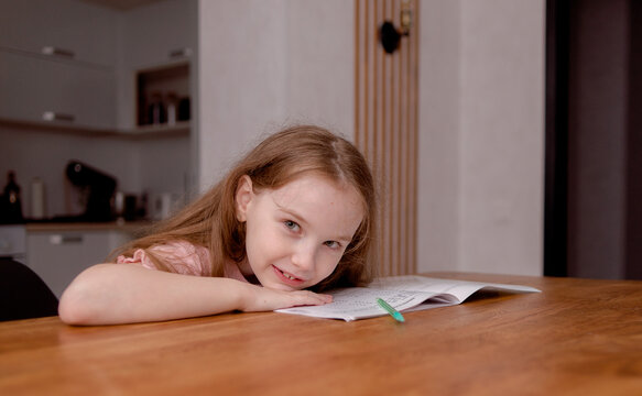 The girl sits at the table and solves problems, does her homework. School theme, vacation assignments