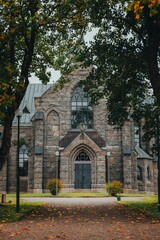Fototapeta na wymiar Facade of the Vallsjo kyrka church in Sweden with autumn trees, vertical shot