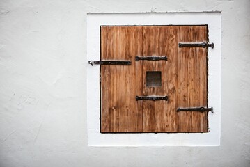Old wooden hatch on a white wall.