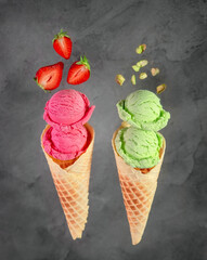 
Strawberry ice cream with strawberries and pistachio with nuts in a waffle cone on a gray background