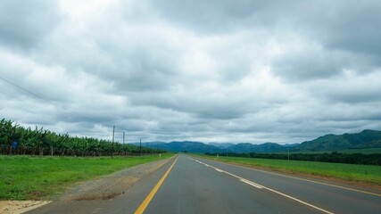 Fototapeta premium Empty, straight asphalt road at a countryside under a cloudy sky