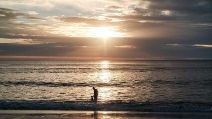 Fototapeta premium Silhouette of a father and a son on a seashore at sunset in Tamarindo, Costa Rica