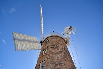 Low angle shot of stone windmill against blue sky