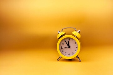 Yellow alarm clock against a yellow background