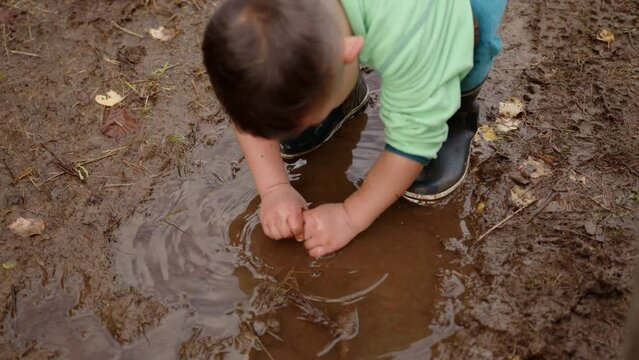 Closeup Footage Of A Small Boy Playing With Mud On A Rainy Day In A Norwegian Forest