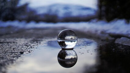 Crystal glass ball on wet ground