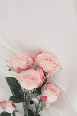 Pink rose flower bouquet on silk fabric beige background.