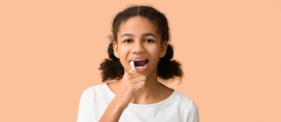 African-American teenage girl brushing teeth on beige background