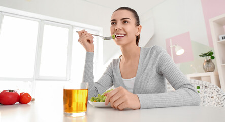 Young woman eating vegetable salad at home