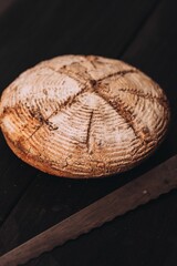Vertical of freshly baked bread with flour and a knife on the table