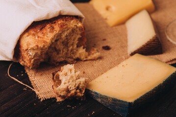 Closeup of a selection of cheese, and fresh baked bread on a wooden table