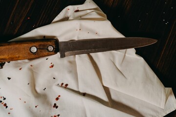a knife sits on the napkin, a napkin is covered with blood