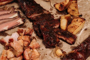 an assortment of meat and potatoes are laying on parchment paper