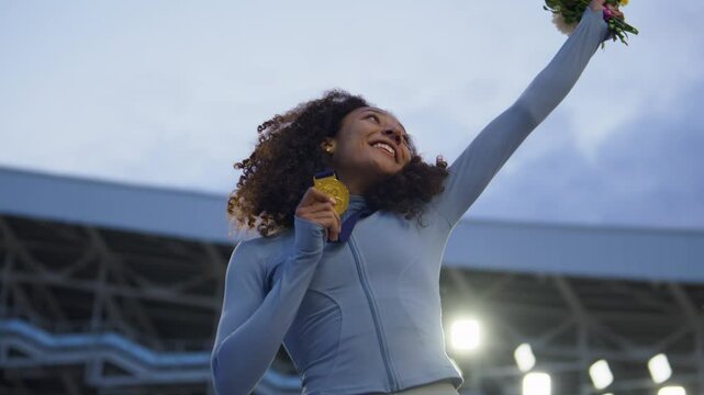 Young African-American Female Athlete Celebrates a Win on a podium, receives a gold medal