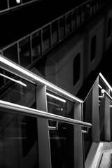 Vertical grayscale shot of modern metallic railings with glass panels