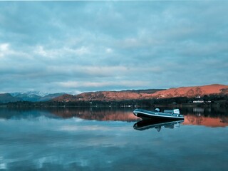 Obraz premium Boat in Ullswater lake in England with hills in the background against a clouded sky