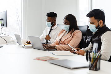 Young multiracial people in business suits wearing face masks working together at office