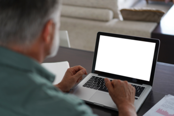Handsome mature man in casual suit sitting at the table in home office and working at laptop