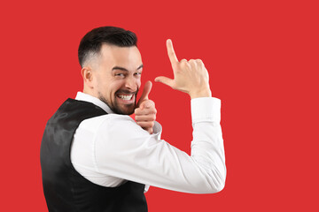 Handsome man showing loser gesture on red background