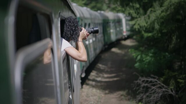 Woman taking photos with mirorrless camera traveling by historical train, slow motion